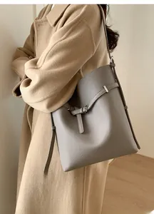 Seitenansicht der grauen Leder-Beuteltasche mit Schultergurt, getragen von einem Model