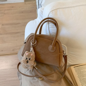 Dettaglio di una borsa Boston marrone in pelle vintage con un grazioso ciondolo a cane