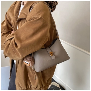 Vue détaillée d'un sac à bandoulière taupe avec fermoir doré et charmant pendentif en peluche