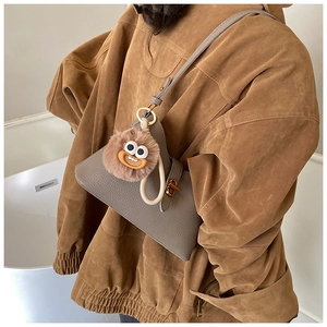 Détail du sac gris à motif lychee avec un joli pendentif de monstre en peluche marron