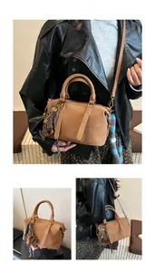 Detailed views of brown Boston bag with dual handles, crossbody strap and woven charm