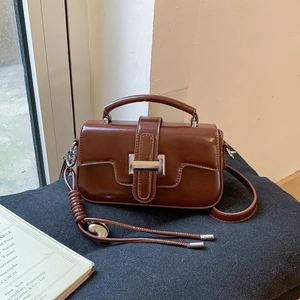Detail of vintage brown PU leather handbag with top handle and silver knot strap
