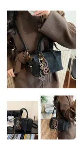 Detail view of black Boston bag with creative pretzel and letter charms on matte leather