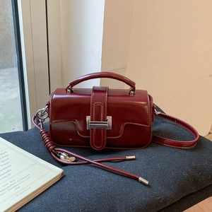 Macro shot of dark red glossy leather bag with silver metal lock and top handle