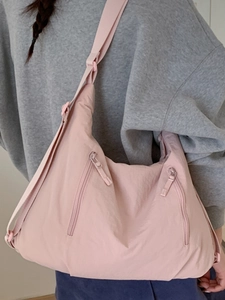 Grand sac fourre-tout rose en nylon avec bandoulière réglable porté par un mannequin