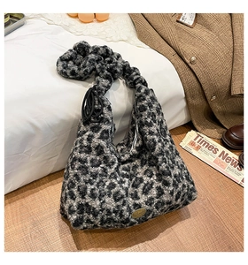 Detail einer Plüschtasche mit Leopardenmuster und Metall-Handmade-Tag auf Holzfoden