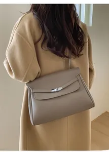 Detailed view of a taupe grained leather tote bag featuring a silver metal twist lock