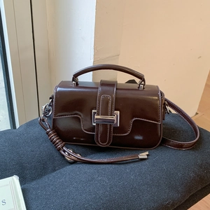 Detail of dark brown patent leather handbag with silver metallic buckle and glossy finish
