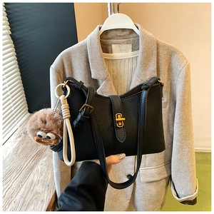 Détail du sac à bandoulière noir en cuir grainé avec fermoir doré et pendentif