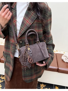 Close-up of a vintage grey Boston bag with rich decorative charms and golden hardware