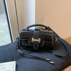 Detail view of glossy black leather bag with a striking rectangular silver metal buckle