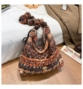 Detail der Strickstruktur der orangefarbenen Hobo-Tasche mit Handmade-Metallemblem