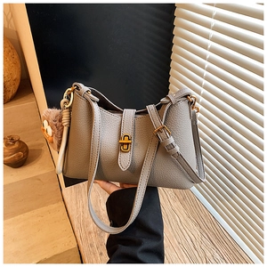 Détail du sac à main gris en cuir grainé avec boucle dorée et breloque en forme de peluche