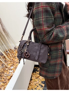Detail of vintage brown Boston bag with unique decorative charms on a textured faux leather