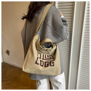 Detail of khaki canvas tote bag with brown logo lettering and wide shoulder strap