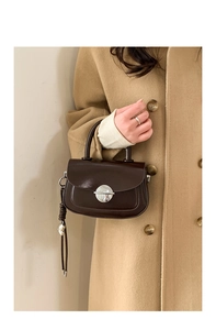 Detail of dark brown mini square bag featuring silver buckle and woven fringe tassels