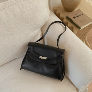 Detail of black lychee grain leather texture and silver metal twist lock on a tote bag