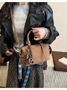 Detailed macro of brown leather boston bag with bonnie charm and braided rope texture
