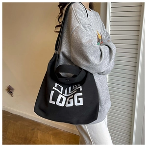 Detail view of large black canvas tote bag with white LOGG print and versatile straps