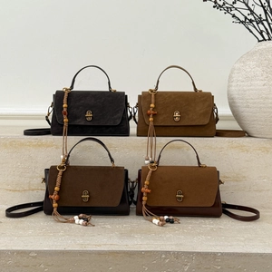Close-up of retro suede handbags with metallic twist locks and tassel details