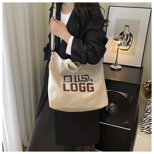 Close-up of cream canvas tote bag with brown lettering showing strap and large capacity
