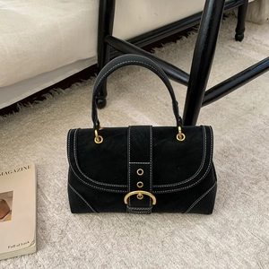 Detailed close-up of a black suede handbag featuring contrast stitching and a large gold ring