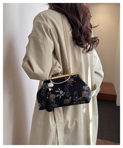 Detail of black silk embroidery handbag with vintage gold clasp and elegant tassel