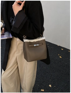 Close-up of brown litchi leather bucket bag with white faux fur trim and silver lock
