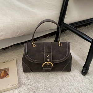 Close-up of retro square handbag featuring white contrast stitching and a gold metal buckle