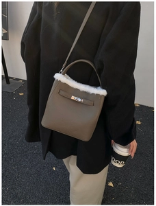 Detail of brown leather bucket bag with white faux fur trim and gold twist lock clasp