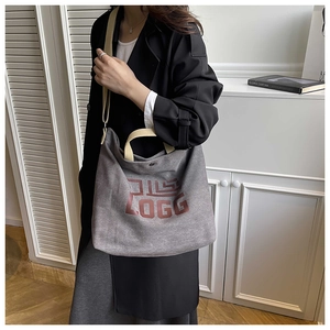 Gray canvas tote bag detail showing red geometric logo print and metal snap closure