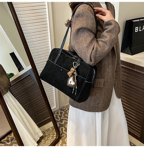 Detail of black suede tote bag featuring contrast white stitching and heart charm detail