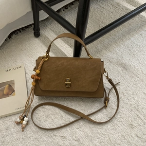 Detailed close-up of brown suede vintage handbag with retro gold clasp and beaded tassel