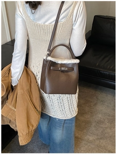Detail of dark brown leather bucket bag with white faux fur trim on a model side view