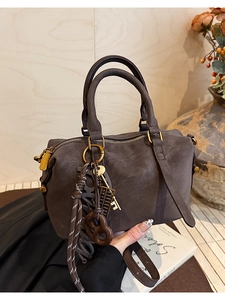 Detail view of vintage dark brown Boston bag featuring unique charms and textured leather