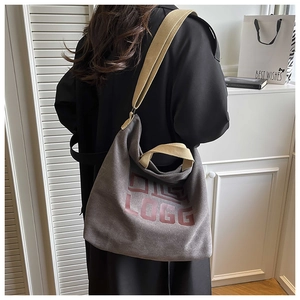 Detailed side view of the spacious canvas tote bag with contrast shoulder straps on a model