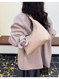 Detail of minimalist apricot Hobo bag with lychee grain texture and plush rabbit charm