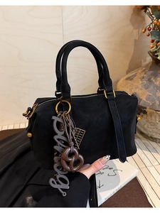 Close-up of black matte leather Boston bag with decorative pretzel and abacus charms
