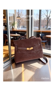 Macro view of vintage brown leather tote bag with gold metal lock and top handle detail