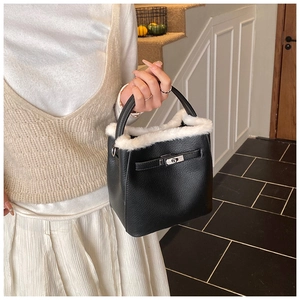 Detail of black lychee grain bucket bag featuring white faux fur trim and silver twist lock