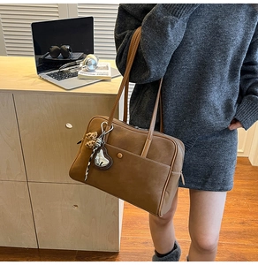 Detailed view of a vintage brown tote bag with contrast stitching and decorative charms