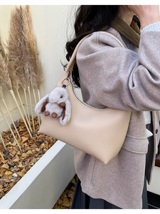 Detail of beige lychee pattern hobo bag with a soft plush rabbit charm attachment