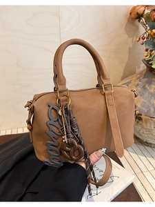 Detail of brown litchi leather Boston bag with 'bonita' charm and golden hardware
