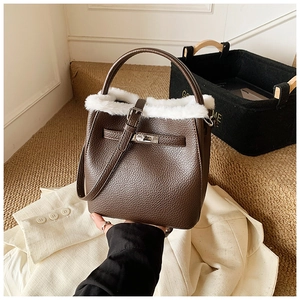 Close-up of brown pebbled leather bucket bag with white faux fur trim and belt buckle lock