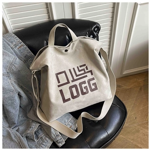 Detailed texture of beige canvas tote bag with brown LOGG print on a leather sofa
