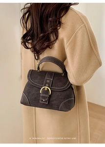 Detail of dark brown retro shoulder bag with white contrast stitching and gold ring buckle