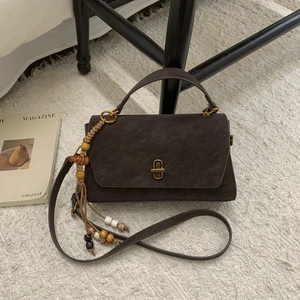Close-up of a vintage dark brown tote bag with metal clasp and woven bead charms