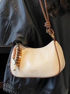 Chic cream crescent shoulder bag with brown trim and wooden bead charm accessory