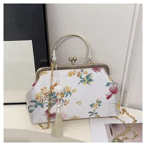 Close-up of white satin evening bag with floral embroidery and gold metal handle
