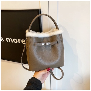 Macro shot of grey lychee leather bucket bag with white faux fur trim and metal lock